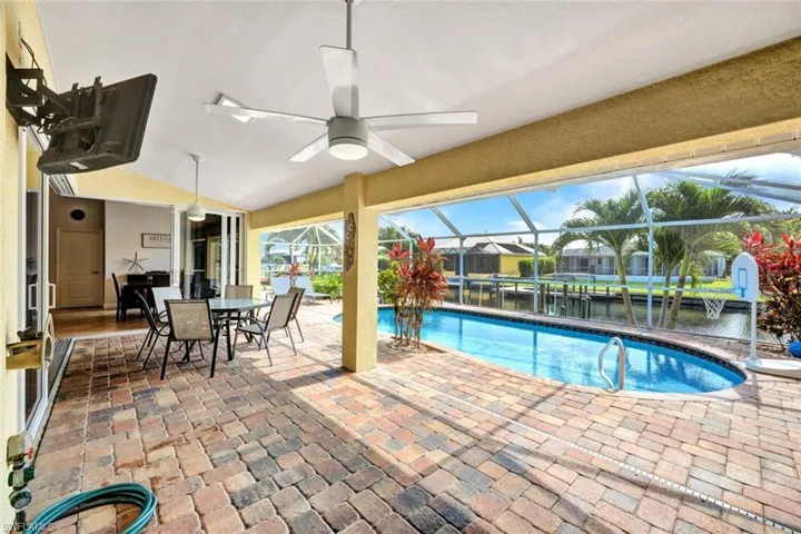 View of swimming pool with ceiling fan, glass enclosure, and a patio area