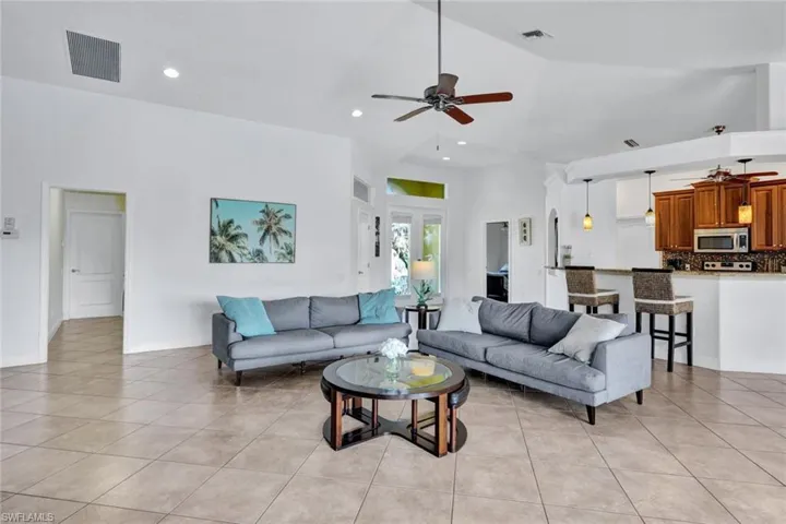Tiled living room with high vaulted ceiling and ceiling fan
