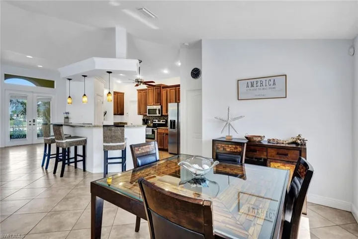 Tiled dining room with vaulted ceiling, ceiling fan, and french doors