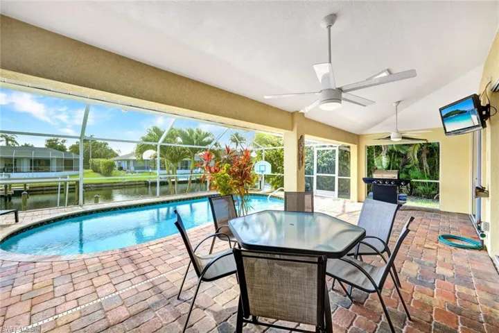 View of swimming pool with a water view, glass enclosure, ceiling fan, area for grilling, and a patio