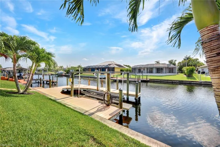 Dock area featuring glass enclosure, a water view, and a yard