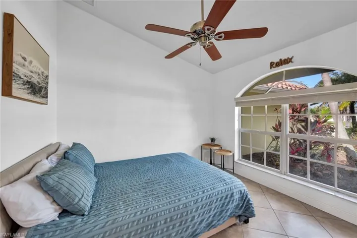 Bedroom with vaulted ceiling, ceiling fan, and light tile floors