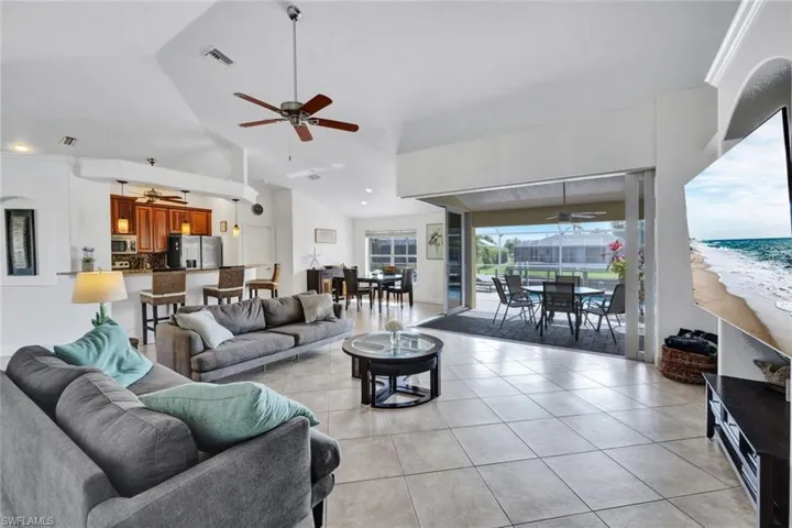 Tiled living room with high vaulted ceiling, a water view, and ceiling fan