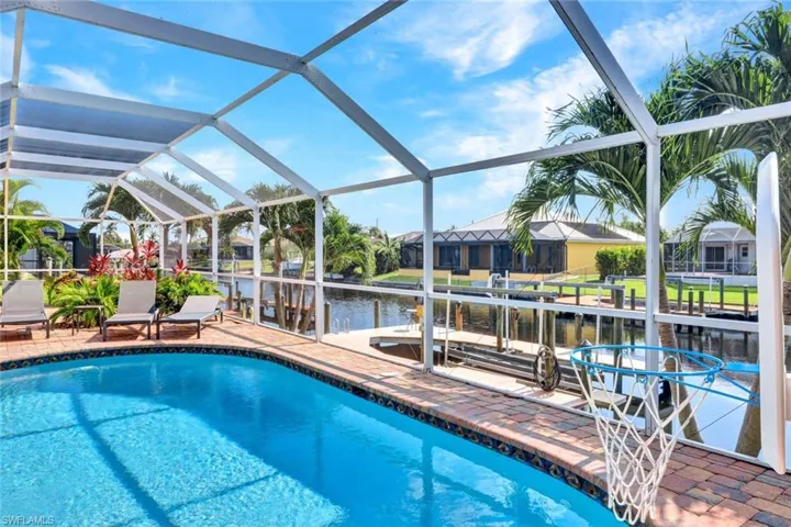 View of pool featuring a patio, glass enclosure, and a dock
