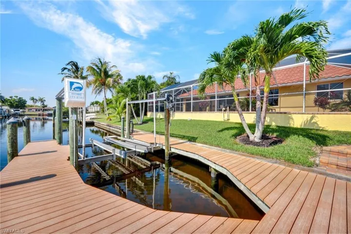 View of dock featuring a yard, glass enclosure, and a water view
