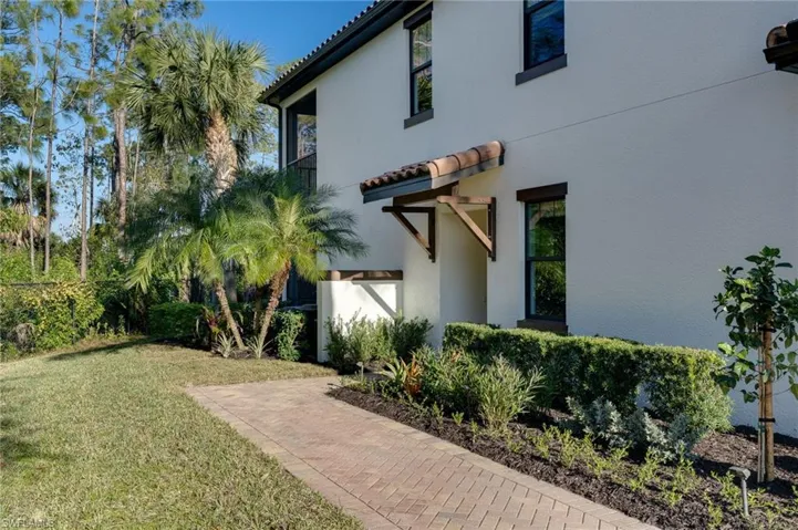View of side of property featuring a lawn, a tile roof, and stucco siding