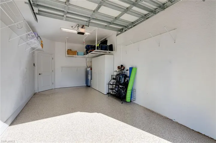 The garage, featuring an epoxy floor, lots of shelving, two ceiling-mounted storage racks, and two white metal cabinets measuring 32" x 72", will convey to the buyer.