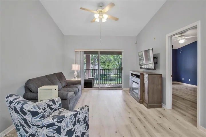 Living room with ceiling fan, light wood-type flooring, and lofted ceiling