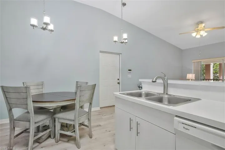 Kitchen featuring light hardwood / wood-style flooring, dishwasher, pendant lighting, sink, and lofted ceiling