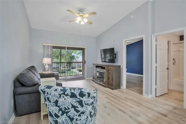 Living room featuring high vaulted ceiling, ceiling fan, and light wood-type flooring