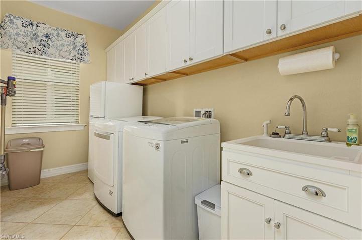 Large laundry room with washer, dryer, wet sink and freezer.
