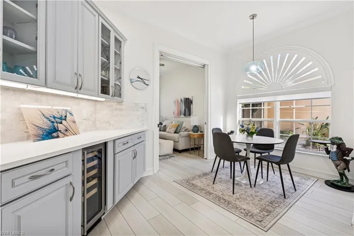 Dining room featuring beverage cooler, ornamental molding, light wood finished floors, and a dry bar