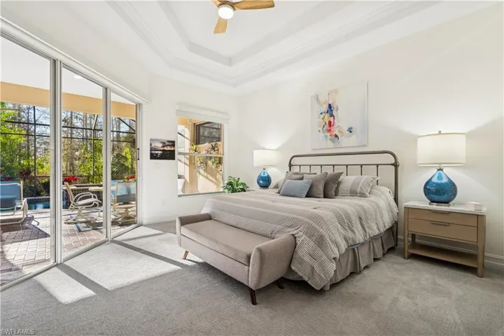 Bedroom featuring light carpet, access to exterior, ceiling fan, crown molding, and a tray ceiling