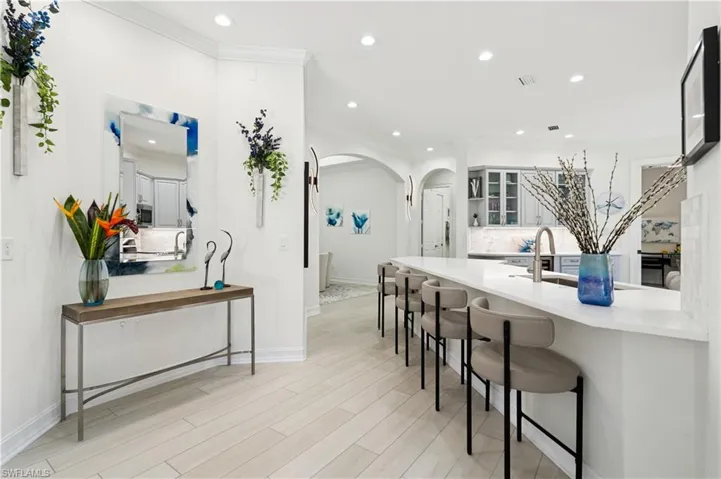 Kitchen with a breakfast bar area, arched walkways, decorative backsplash, glass fronted cabinets, and light wood-style floors