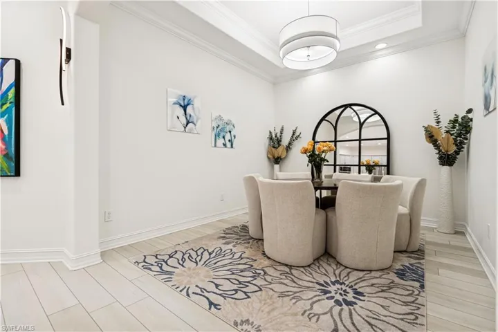 Dining room featuring wood finish floors, a tray ceiling, and crown molding