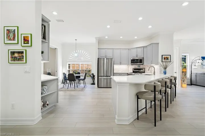 Kitchen featuring a peninsula, stainless steel appliances, a kitchen bar, gray cabinets, and pendant lighting