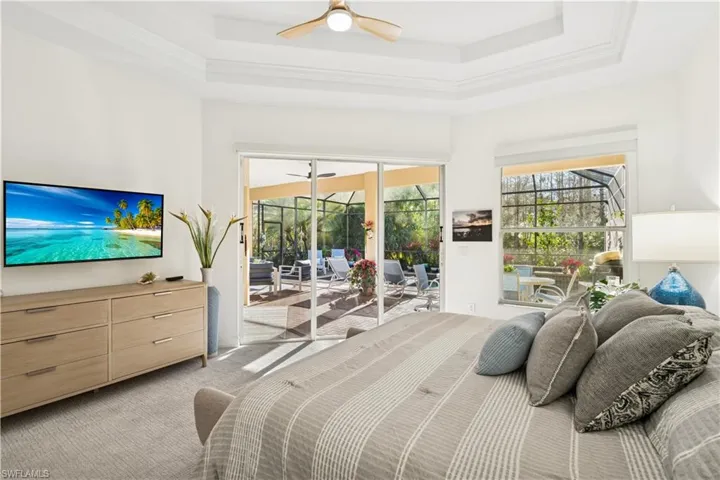 Bedroom featuring a sunroom, light carpet, access to exterior, ceiling fan, and a raised ceiling