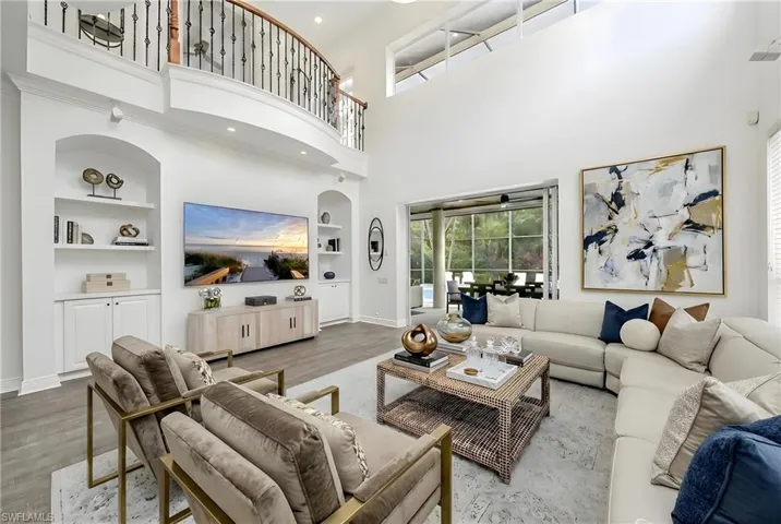 Living area with built in features, wood finished floors, recessed lighting, and a high ceiling