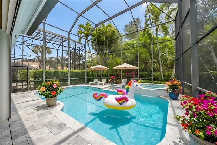 Relaxing pool / spa featuring a sunroom, glass enclosure, and a patio area