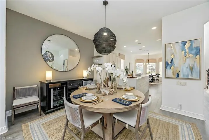 Dining area featuring arched walkways, wine cooler, light wood-style floors, and recessed lighting
