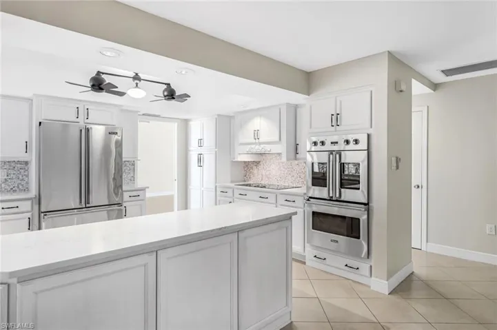 Kitchen with white cabinets, decorative backsplash, light tile patterned flooring, and appliances with stainless steel finishes