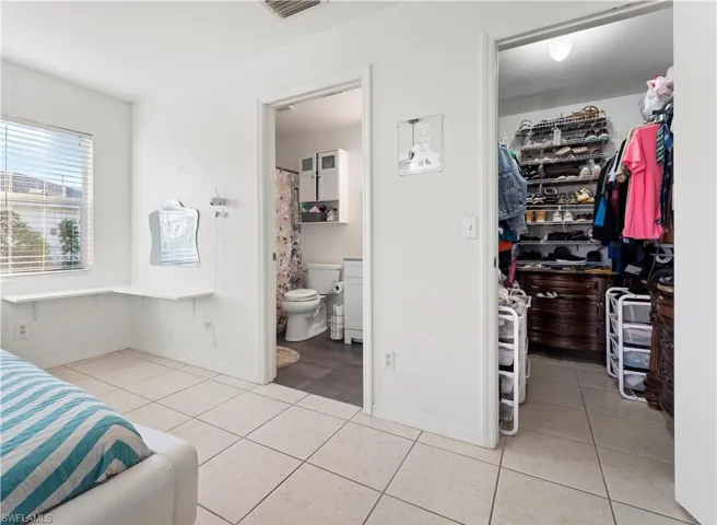 Bedroom featuring a spacious closet, light tile patterned floors, a closet, and ensuite bathroom