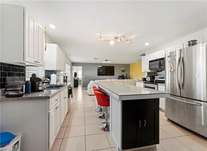 Kitchen with appliances with stainless steel finishes, light tile patterned floors, backsplash, open floor plan, and recessed lighting