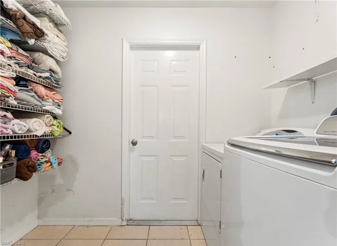 Laundry area with washer and dryer and light tile patterned floors