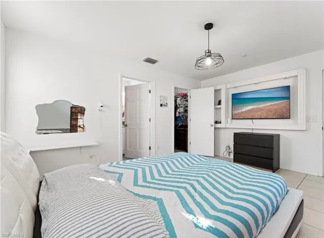 Bedroom with a walk in closet, tile patterned flooring, and a closet