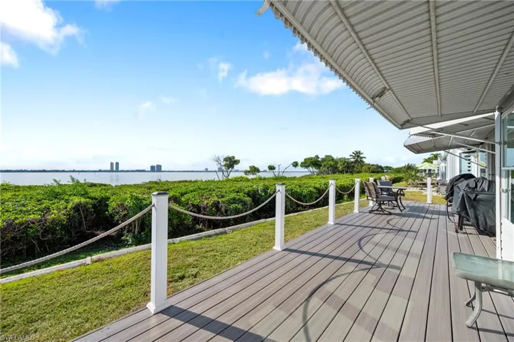 Deck with a water view, a lawn, and outdoor dining space
