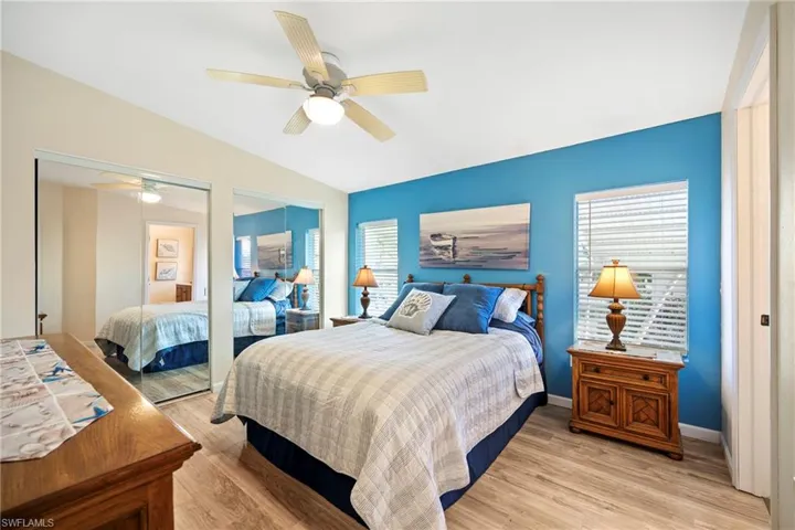 Bedroom with multiple closets, light wood-style floors, vaulted ceiling, and ceiling fan