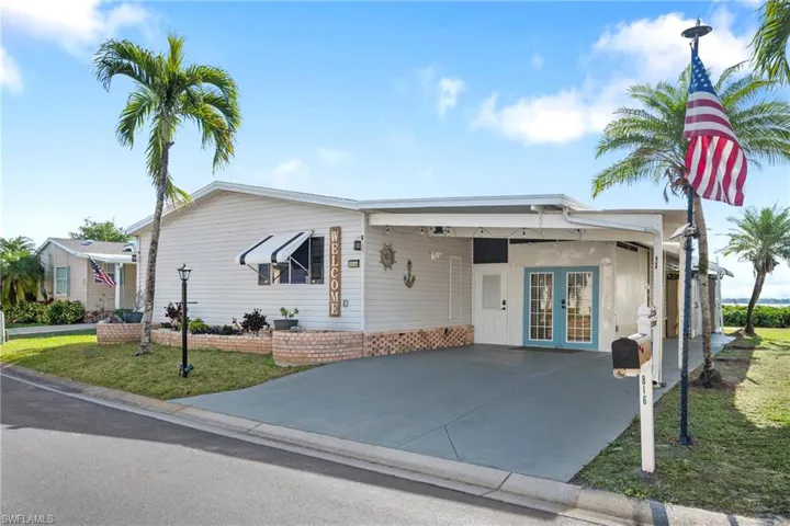 View of front facade with concrete driveway, a carport, a front yard, french doors, and a patio area