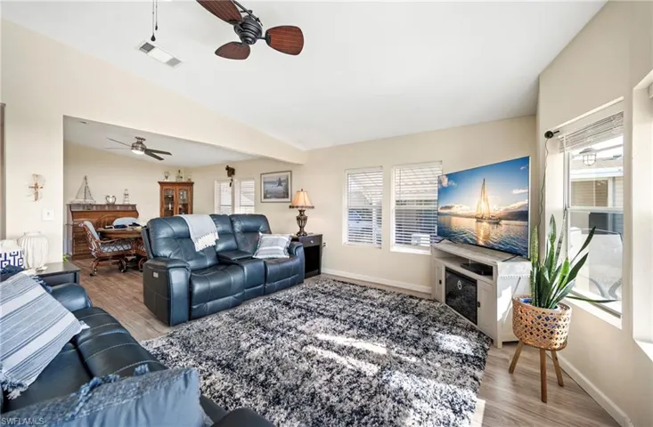 Living room with light wood finished floors, vaulted ceiling, and ceiling fan