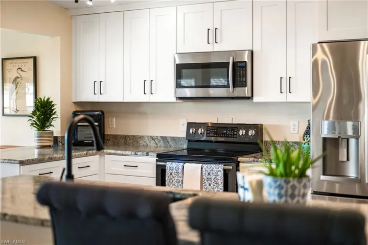 Kitchen with appliances with stainless steel finishes, dark stone countertops, and white cabinets