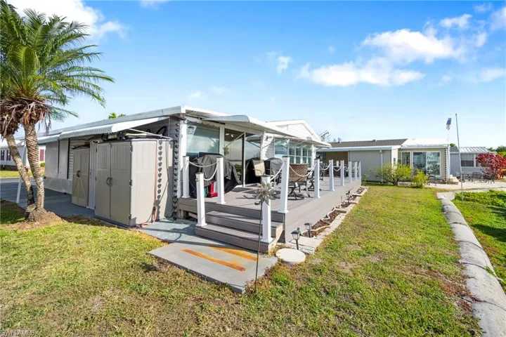 Back of house with a deck and a lawn
