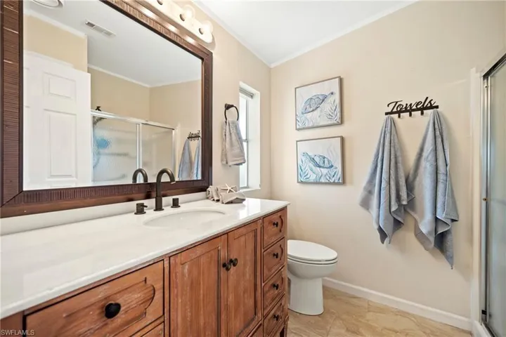 Bathroom featuring a shower stall, crown molding, and vanity