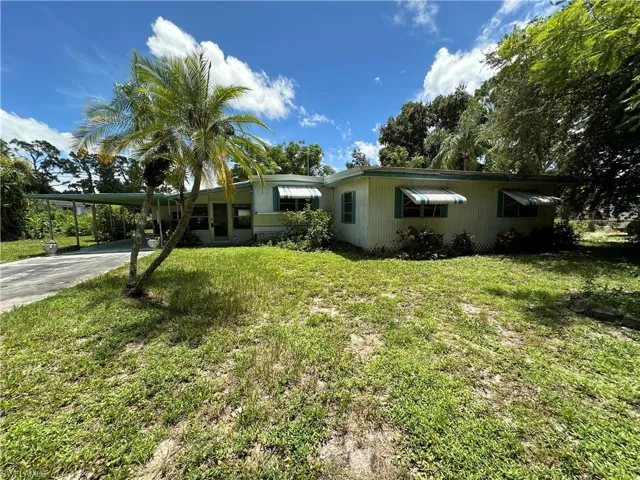 View of front facade featuring a carport and a front lawn