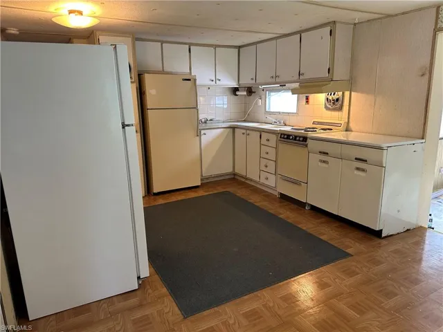Kitchen featuring white appliances, and light parquet flooring