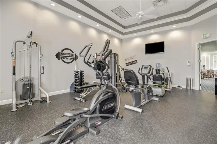 Gym with a ceiling fan, a drop ceiling, a high ceiling, and recessed lighting