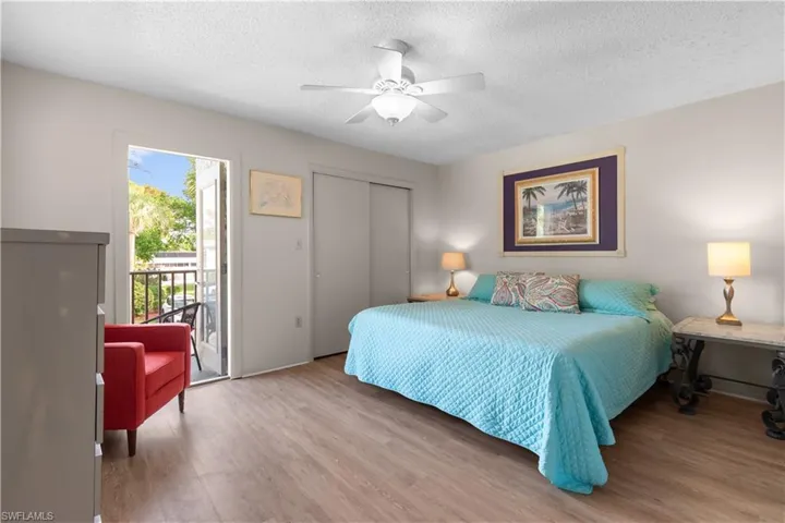 Primary bedroom featuring access to balcony, LVP floors, a textured ceiling, a closet, and ceiling fan