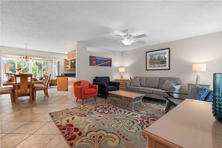 Living room with a textured ceiling, a chandelier, ceiling fan, and light tile patterned flooring