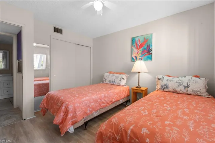 Bedroom featuring a closet, wood finished floors, a textured ceiling, a ceiling fan, and ensuite bath