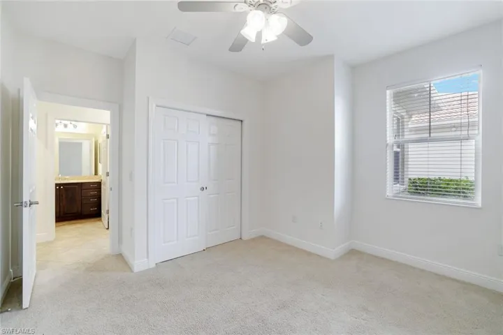 Unfurnished bedroom with light carpet, a closet, ceiling fan, and connected bathroom