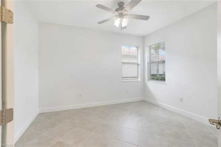 Empty room with light tile patterned flooring and ceiling fan