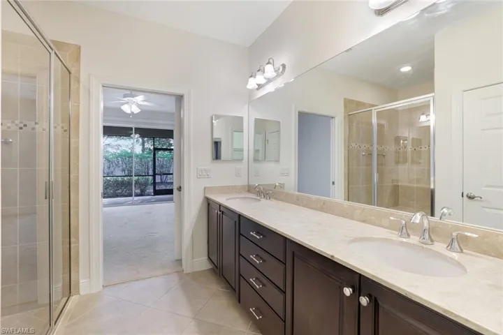 Full bath with light tile patterned floors, double vanity, a shower stall, and light colored carpet