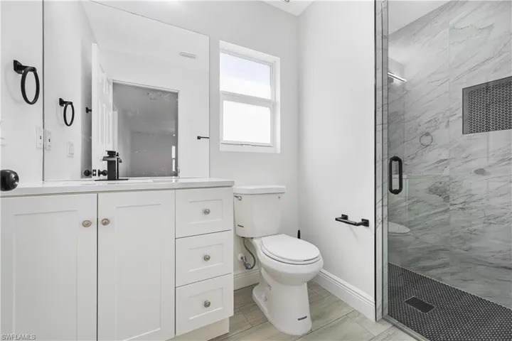 Bathroom featuring vanity and a marble finish shower