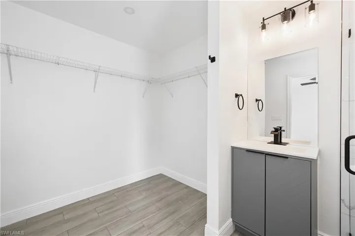 Walk in closet featuring light wood-style flooring and a vanity