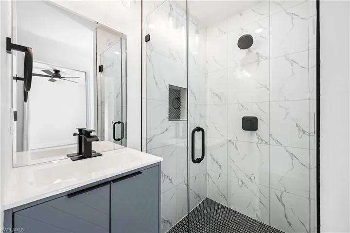 Bathroom with vanity and a marble finish shower
