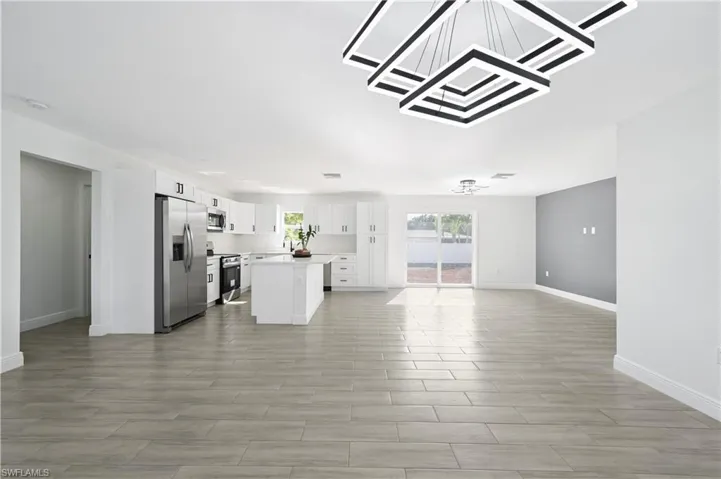 Kitchen with white cabinetry, stainless steel appliances, a center island, open floor plan, and Tile finish floors