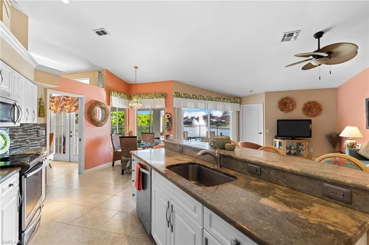 Kitchen with white cabinetry, granite countertops, stainless steel appliances, decorative light fixtures, and vaulted ceiling